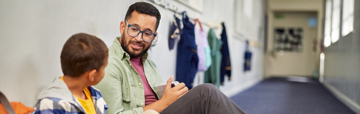 a teacher and student are talking in a hallway at school